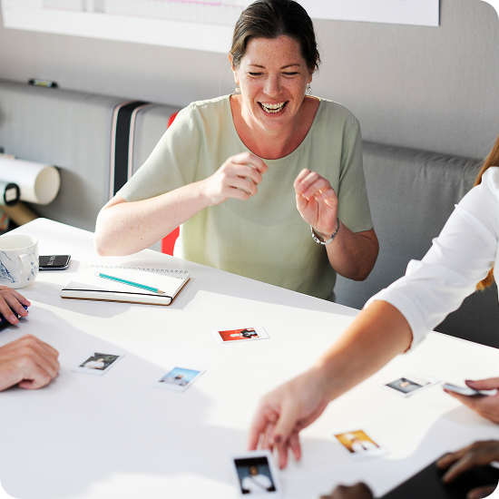 Woman laughing while playing a learning card game with colleagues