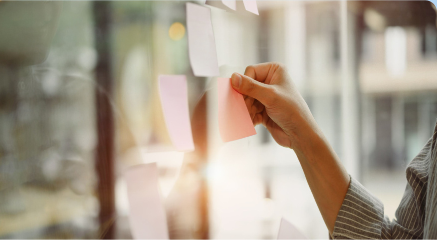 Sticky notes being placed on a glass wall during a planning session